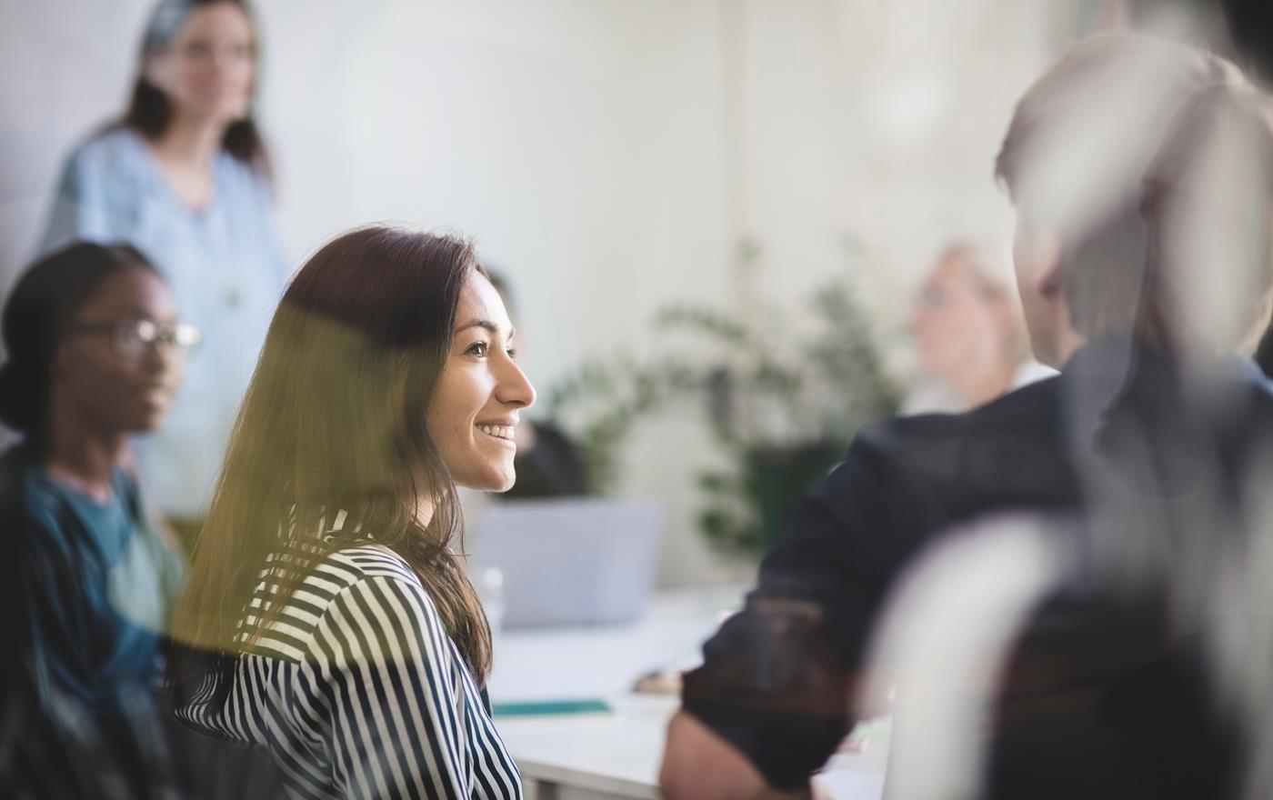 Woman sitting by a table in a meeting room smiling